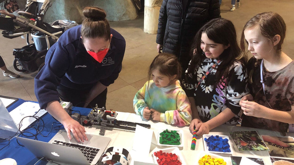 image of a DNALC faculty member showing 3 children the DNA sequencer